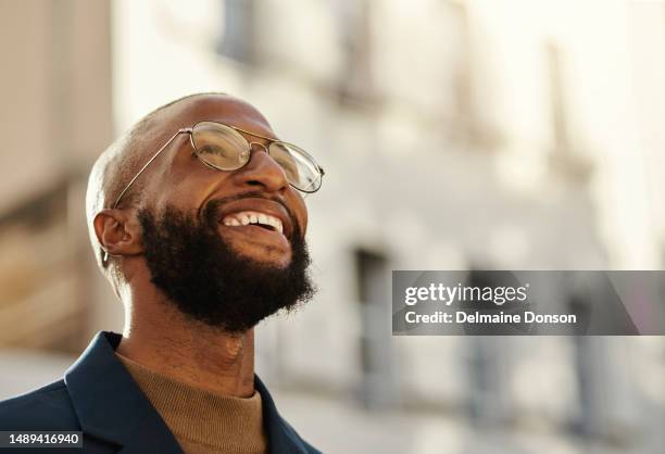 retrato al aire libre de un ambicioso hombre de negocios negro mirando hacia arriba mientras sonríe en la ciudad. foto de archivo - villa asentamiento humano fotografías e imágenes de stock