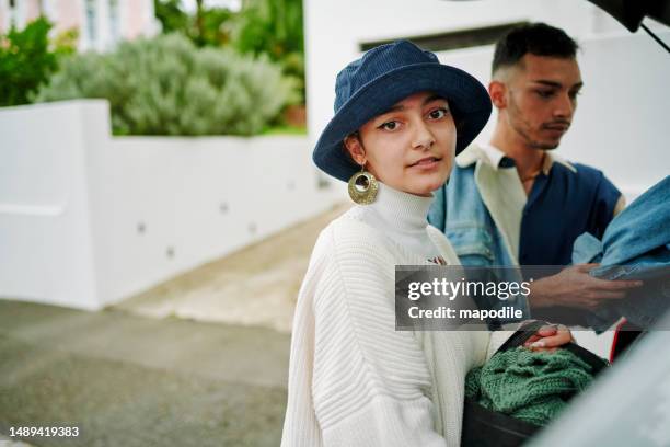 closeup portrait of young  non-binary person looking at camera while packing a car for a road trip - non motorised vehicle stock pictures, royalty-free photos & images