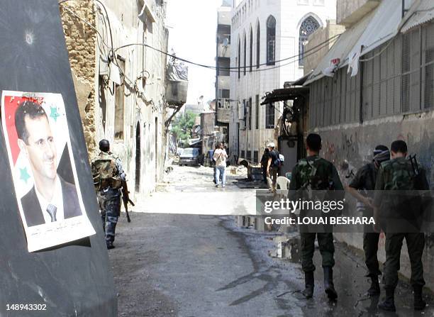 Portrait of Syrian President Bashar Al-Assad hangs on a wall as Syrian soldiers walk past during a government guided tour for journalists of the...