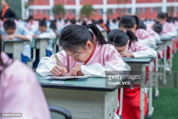 Students sitting at desks write ancient Chinese prose on the playground of Bijie Liangcai School Guizhou Proince on May 12, 2023 in Bijie, Guizhou...