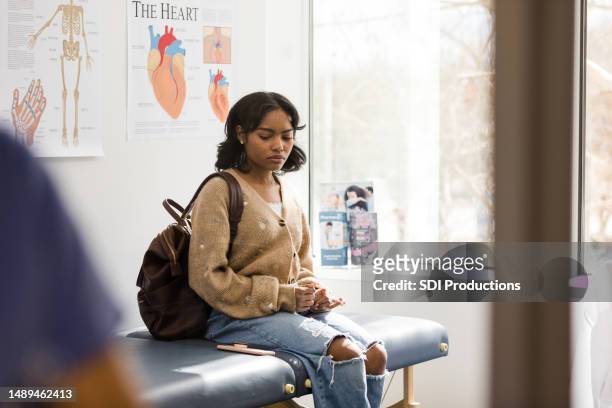 distraught teen girl waits in doctor's examination room - fragile stock pictures, royalty-free photos & images