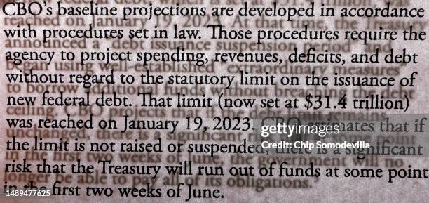 Page from the Congressional Budget Office's "An Update to the Budget Outlook: 2023 to 2033" is superimposed on the preceding page in a photograph on...