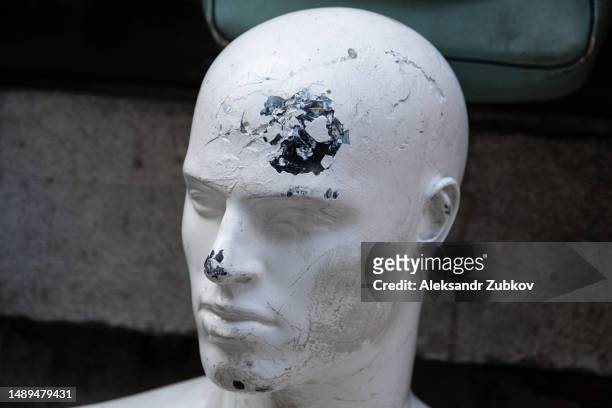 a broken and abandoned mannequin, in a faded condition. a dummy that is no longer in use. the face of a broken mannequin in the used clothing market area. an old worn-out mannequin with cracks and breakages. an old android, a cyborg. - broken mannequin stock pictures, royalty-free photos & images