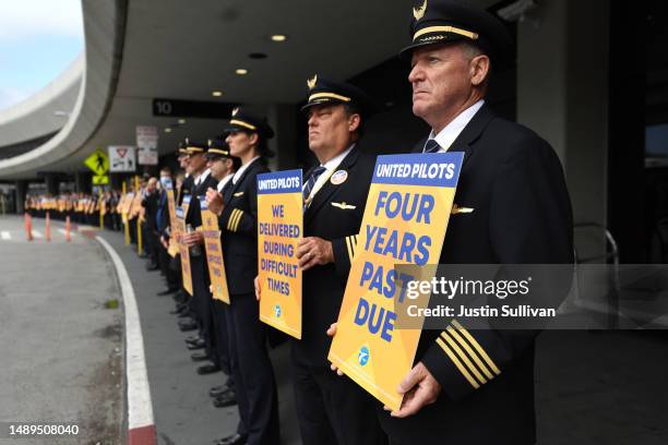 United Airlines pilots hold signs in front of the United Airlines terminal at San Francisco International Airport on May 12, 2023 in San Francisco,...