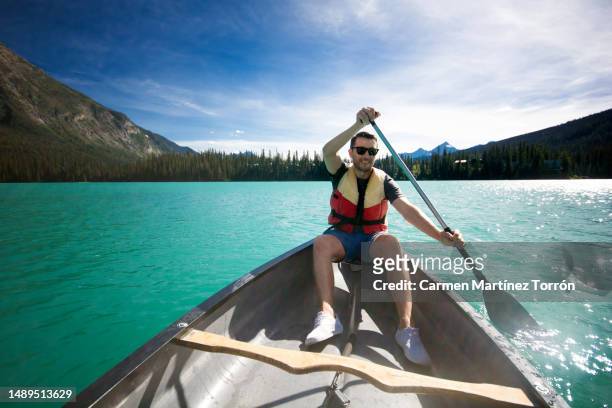 man canoeing on a turquoise emerald lake in canada. - k2 kayaking stock pictures, royalty-free photos & images