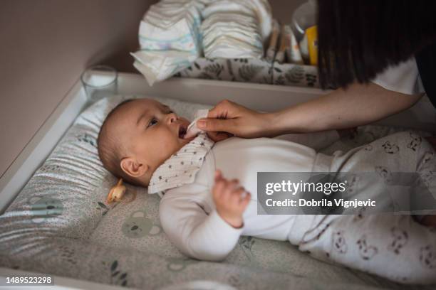 woman massaging baby's gums - eruption stockfoto's en -beelden