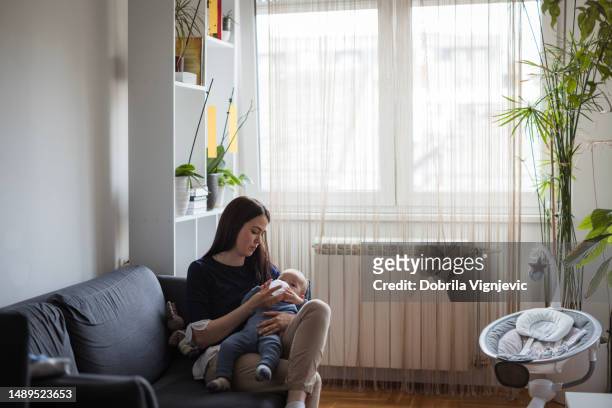 woman feeding her baby infant formula - mother son milk imagens e fotografias de stock