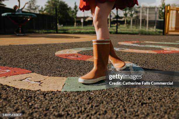 close-up of a child's feet walking across an alphabet snake in a play park - snakes and ladders stock pictures, royalty-free photos & images