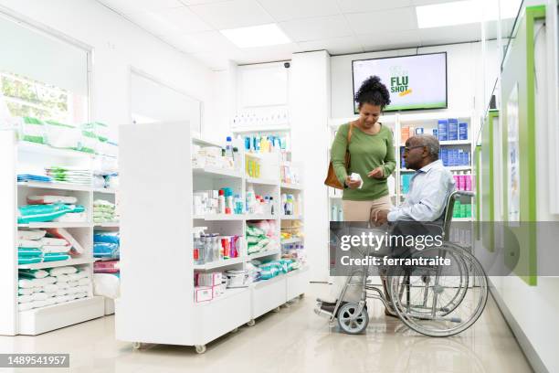 healthcare worker helping disabled senior man shopping in pharmacy - chemist shop stock pictures, royalty-free photos & images