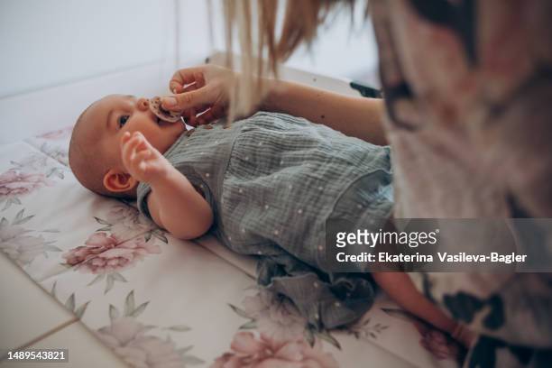 mother gives her newborn daughter a pacifier - hand over mouth stock pictures, royalty-free photos & images
