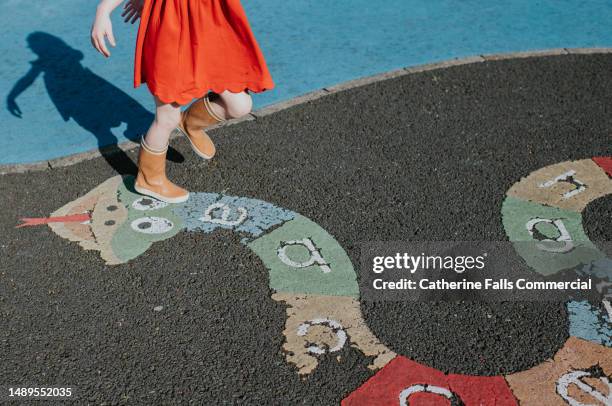 a child walks over an alphabet snake in a playpark - snakes and ladders stock pictures, royalty-free photos & images