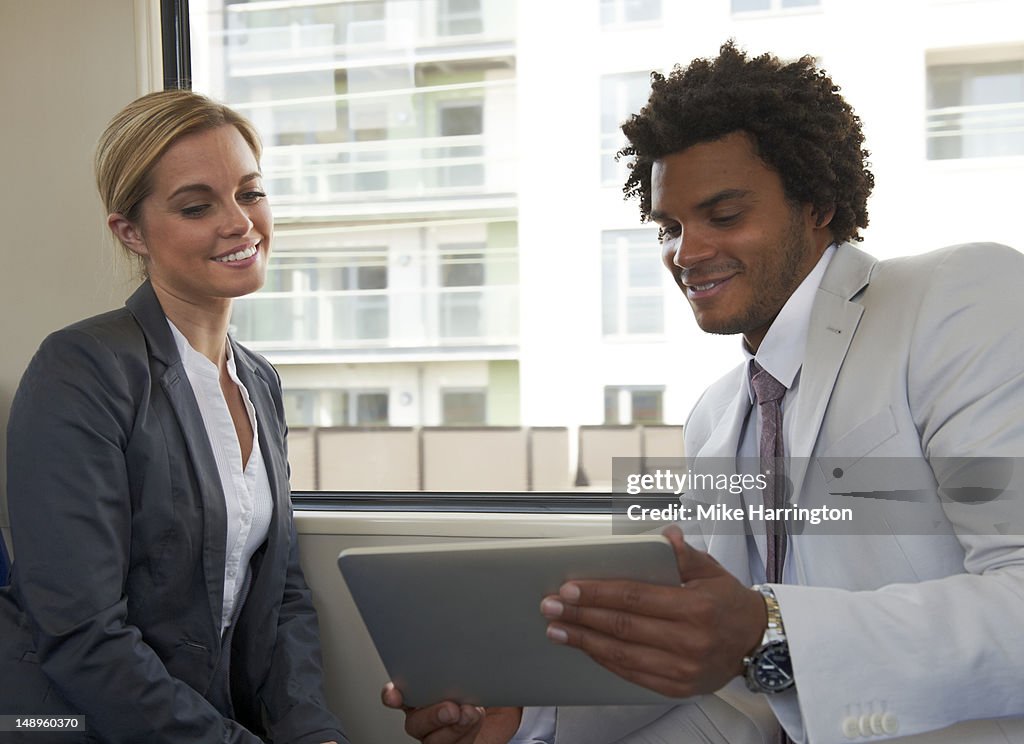 Male and Female Using tablet computer on Train