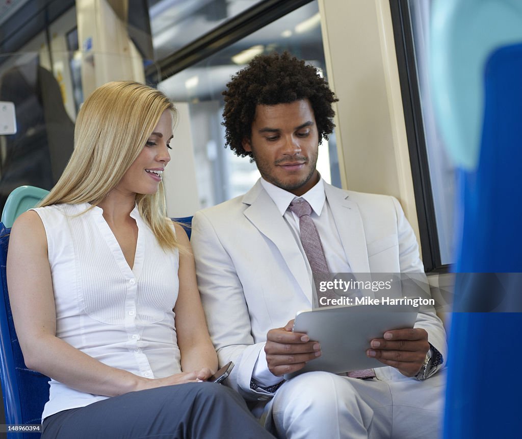 Male and Female Using tablet computer on Train