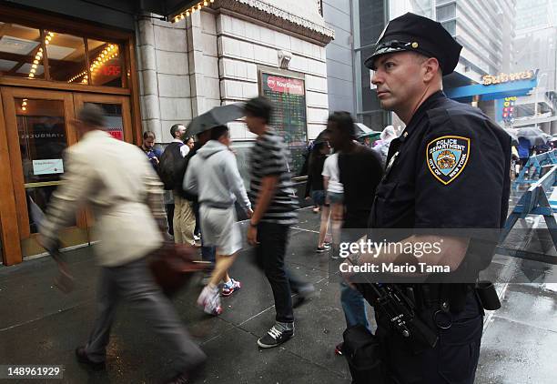 An NYPD officer keeps watch in front of an AMC move theater where the film 'The Dark Knight Rises' is playing in Times Square on July 20, 2012 in New...