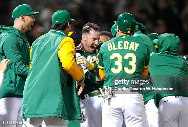 Brent Rooker of the Oakland Athletics celebrates with teammates after hitting a walk-off three-run home run to defeat the Texas Rangers 9-7 in the...