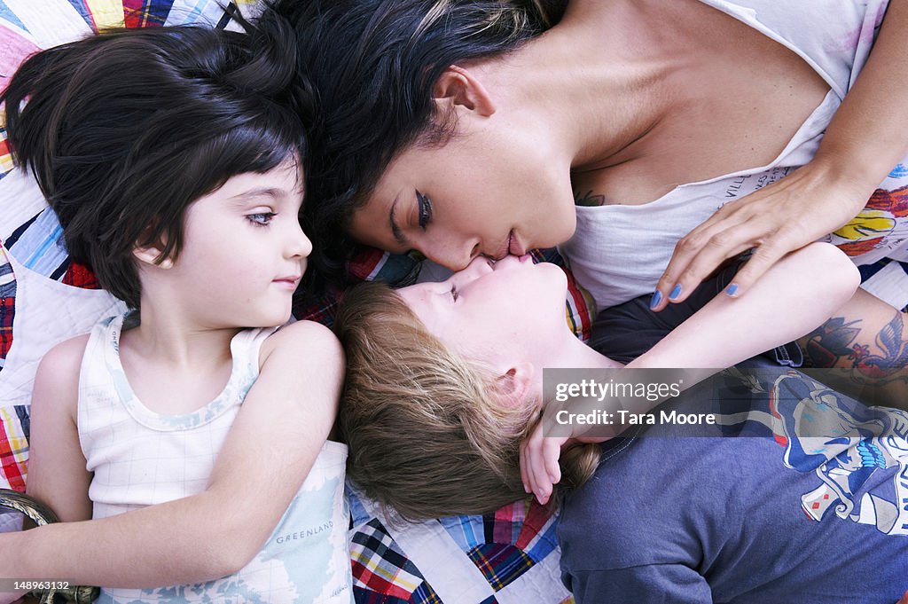 Mother lying on bed with two sons