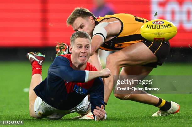 Lachie Hunter of the Demons handballs whilst being tackled by Harry Morrison of the Hawks during the round nine AFL match between Hawthorn Hawks and...
