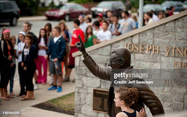 Visitors pose for photographs with the statue of former Penn State University football coach Joe Paterno outside Beaver Stadium July 20, 2012 in...