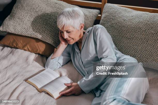 a happy beautiful woman in pajamas relaxing at home - ler um livro imagens e fotografias de stock