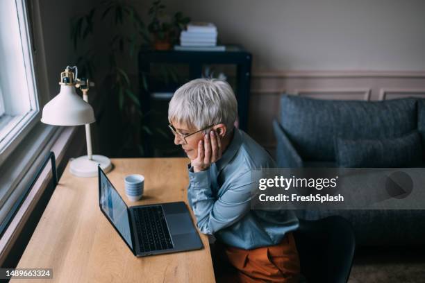 a from above view of a serious beautiful businesswoman with glasses working from home on her computer - casual woman pensive side view stockfoto's en -beelden