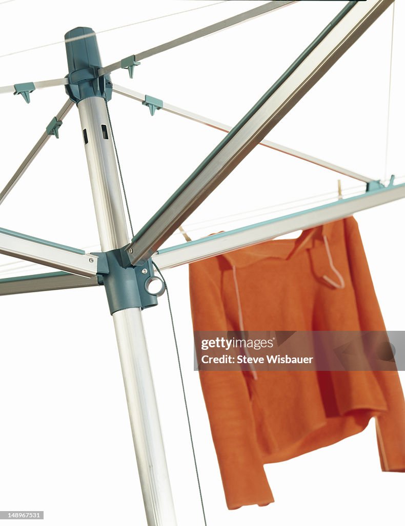 An orange sweater on an umbrella clothesline