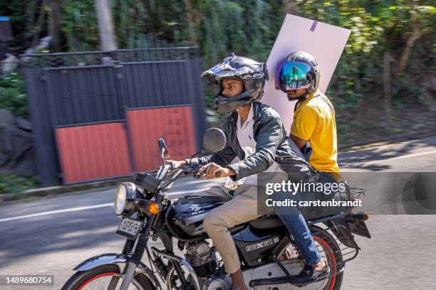 zwei junge männer auf einem motorrad mit einem großen flachen paket - kandy kandy district sri lanka stock-fotos und bilder