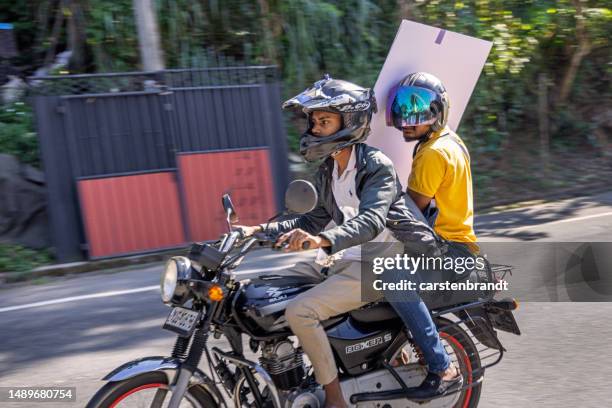 dos jóvenes en una motocicleta con un paquete plano grande - kandy kandy district sri lanka fotografías e imágenes de stock