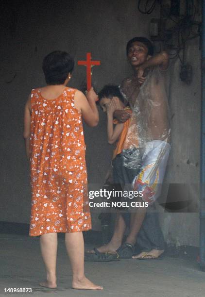 Woman holds a cross towards hostage taker Remer Parparan as he points an icepick at 10 years old Jason Pineda during a hostage taking incident in...