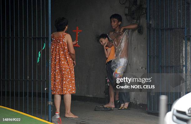 Woman holds up a cross towards hostage taker Remer Parparan as he points an icepick at 10 years old Jason Pineda during a hostage taking incident in...