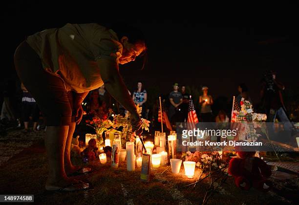 Woman lights candles at a makeshift memorial during a vigil for victims of the Century 16 movie theatre where a gunmen attacked movie goers during an...