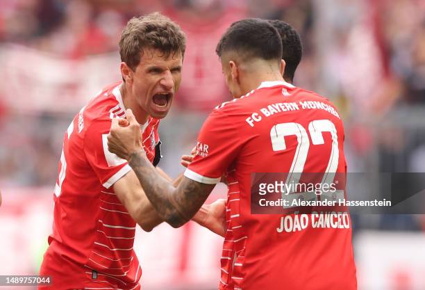Thomas Mueller of FC Bayern Munich celebrates with teammate Joao Cancelo after scoring the team's first goal during the Bundesliga match between FC...