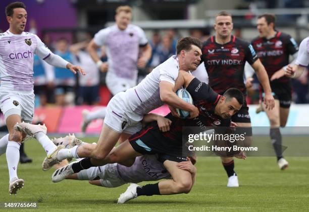 Alex Lozowski of Saracens is tackled by George Furbank and Fin Smith of Northampton Saints during the Gallagher Premiership Semi-Final match between...