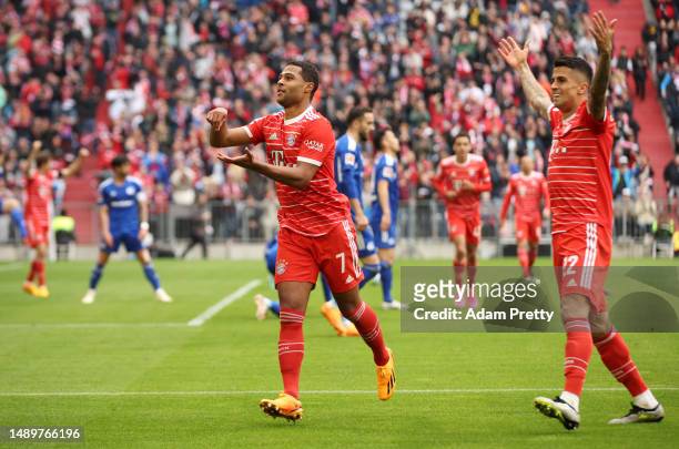 Serge Gnabry of FC Bayern Munich celebrates with teammate Joao Cancelo after scoring the team's third goal during the Bundesliga match between FC...