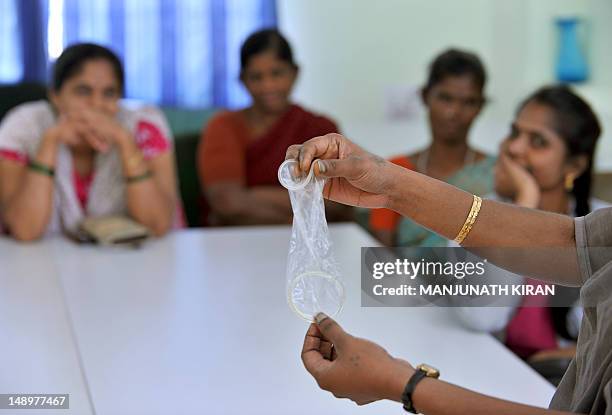 Project coordinator displays a female condom to HIV-positive patients and affected family members during an awareness session at the Asha Foundation,...