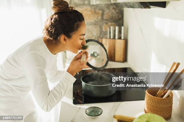 woman making lunch in the kitchen and stirring soup. - suppe stock-fotos und bilder