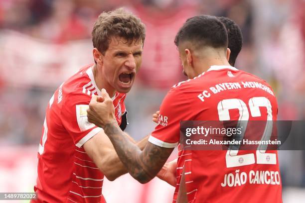 Thomas Mueller of FC Bayern Munich celebrates with teammate Joao Cancelo after scoring the team's first goal during the Bundesliga match between FC...