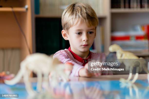 niño mirando el juguete de dinosaurio con lupa y curiosidad - enciclopedia fotografías e imágenes de stock