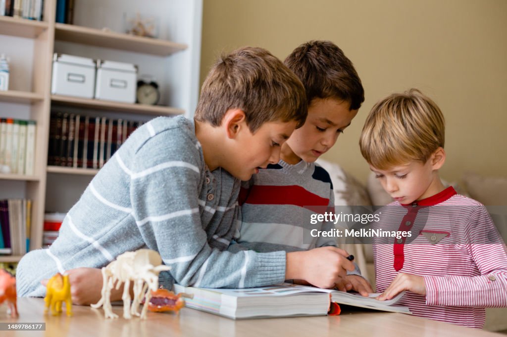 Gruppe von Kindern, die Enzyklopädie über Paläontologie und Dinosaurier lesen