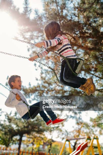 glückliche kinder, die im park schaukeln - schaukel stock-fotos und bilder