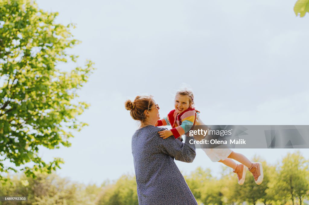 Happy mom carrying her little daughter