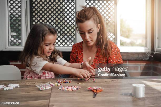 happy girl and mom making string bracelets - bead string stock pictures, royalty-free photos & images