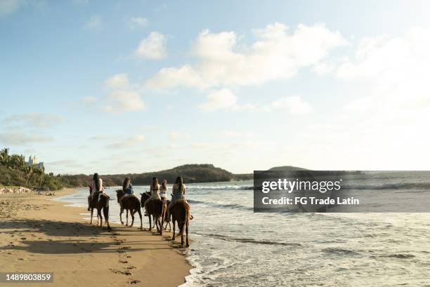 female friends during horseback riding on the beach - horseback riding stock pictures, royalty-free photos & images