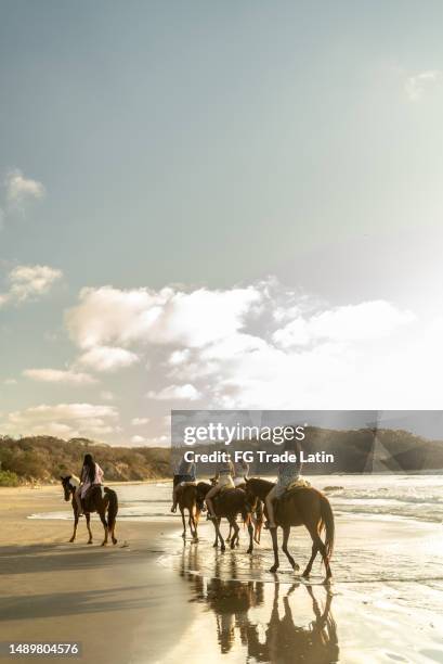 female friends during horseback riding on the beach - horseback riding stock pictures, royalty-free photos & images