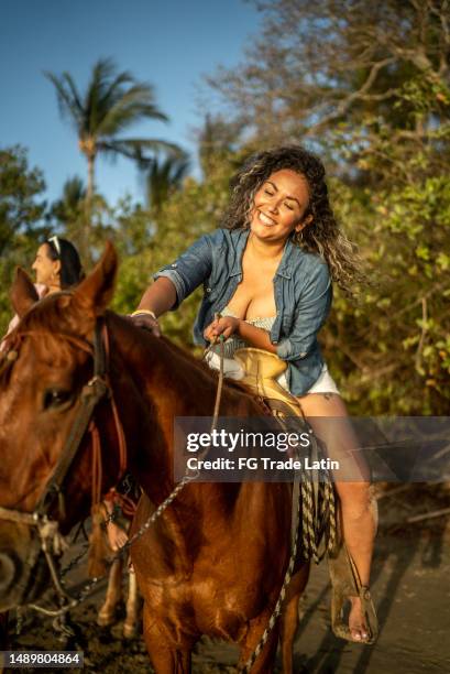 mid adult woman doing horse back riding on the beach - pat on the back stockfoto's en -beelden