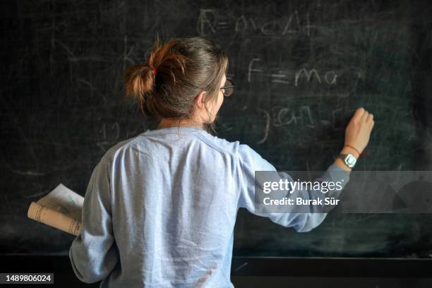 young female student studying at blackboard, education, back to school, exam preparations - lärare bildbanksfoton och bilder