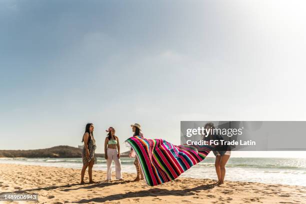 female friends preparing yoke to sit on the beach - strandhanddoek stockfoto's en -beelden