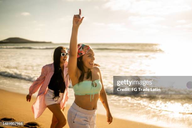 amiche che si divertono mentre camminano sulla spiaggia - accessory foto e immagini stock