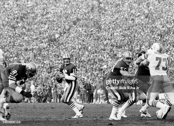 San Francisco QB Joe Montana scrambles out of the reach of Dolphins DE Kim Bokamper during game action at Super Bowl XIX of Miami Dolphins vs. San...