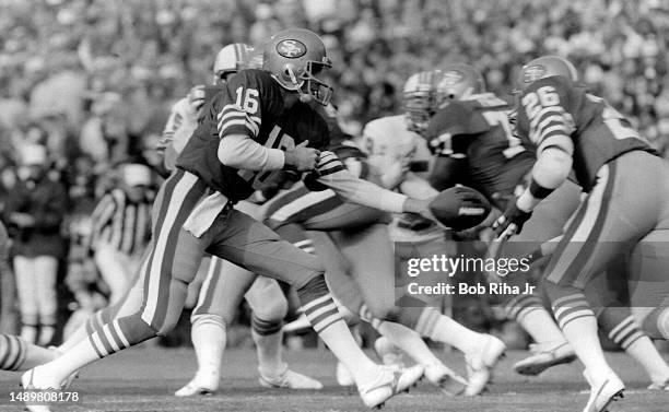 San Francisco QB Joe Montana scrambles out of the reach of Dolphins DE Kim Bokamper during game action at Super Bowl XIX of Miami Dolphins vs. San...