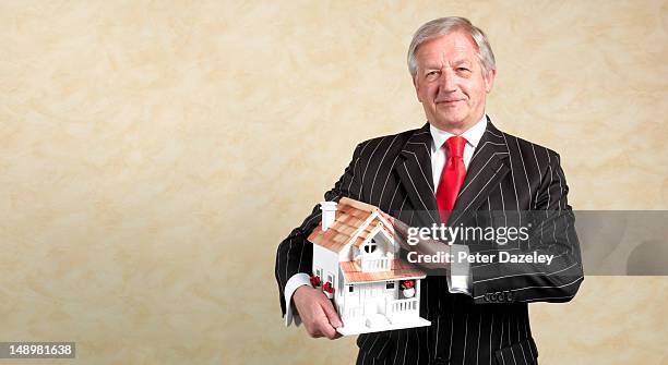 senior estate agent with a model house - striped suit 個照片及圖片檔